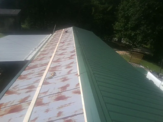 Old rusted panels beside newly installed green metal roofing — Wind Damage Roof Repair by Roofing Brothers in Reisterstown