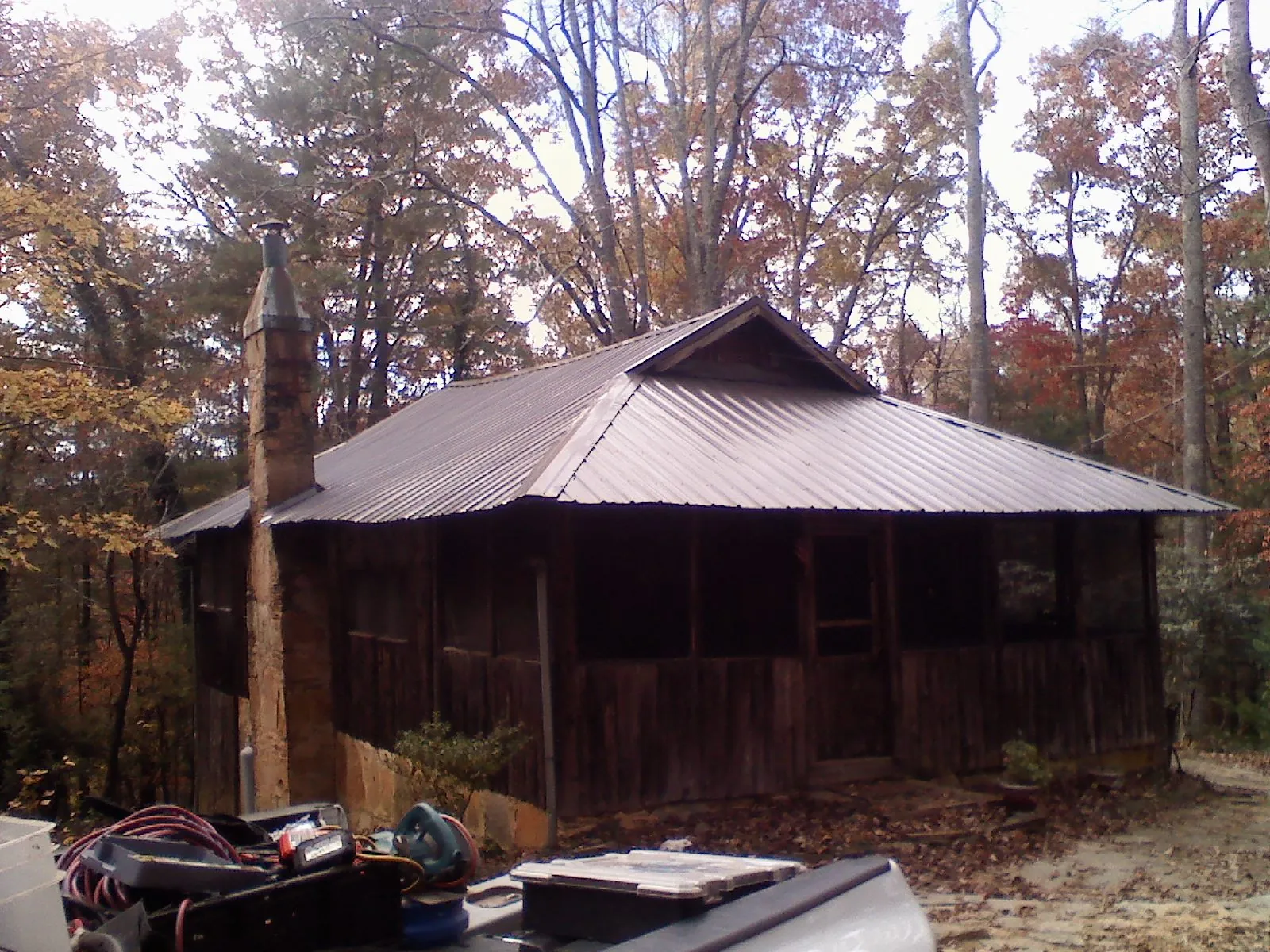 Brown metal hip roof on an old cabin with a stone chimney in Reisterstown