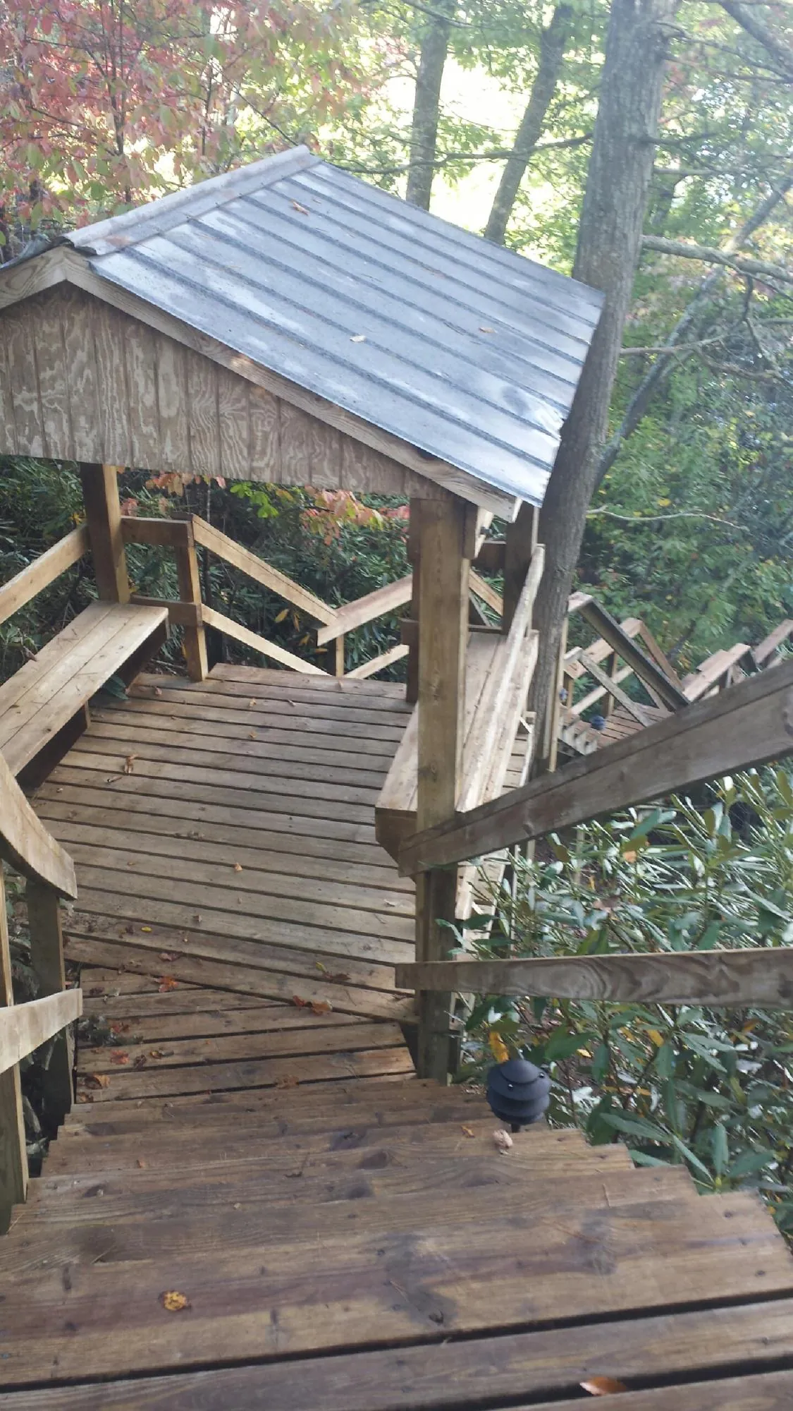 Metal roofed shelter over wooden steps on a wooded walkway — Skylight Repair & Installation work by our crew in Reisterstown