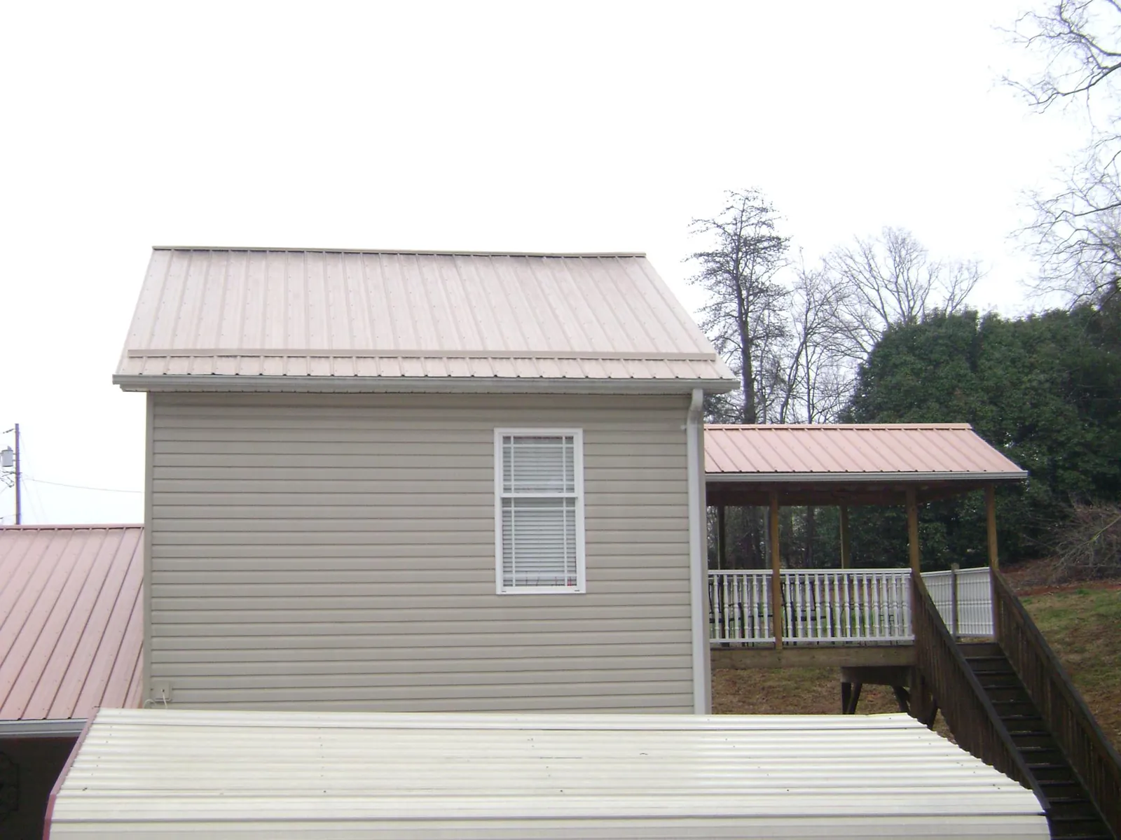 Tan metal roofs on a two story addition and attached porch, from a Roof Replacement job in Reisterstown