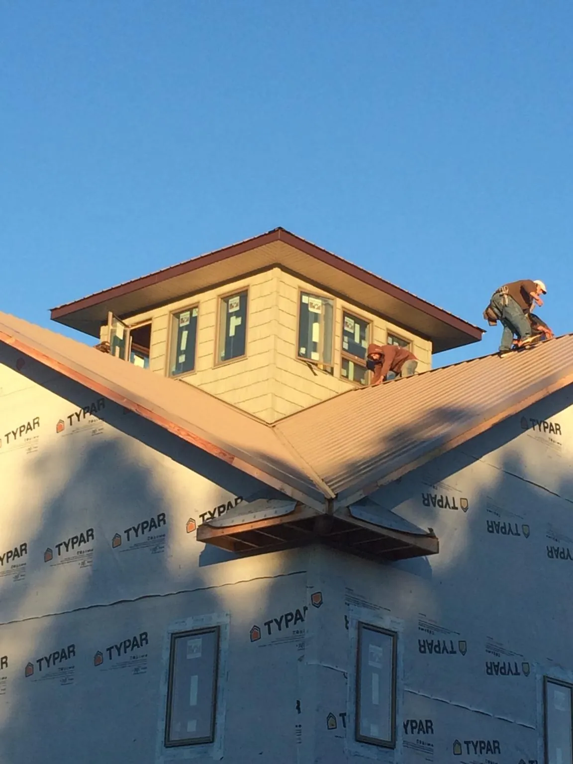 Roofers working around a rooftop cupola on a new metal roof at sunset — Roof Waterproofing in Reisterstown by Roofing Brothers